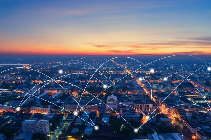 Aerial view of buildings and homes with illustrated lines representing power grid connection.