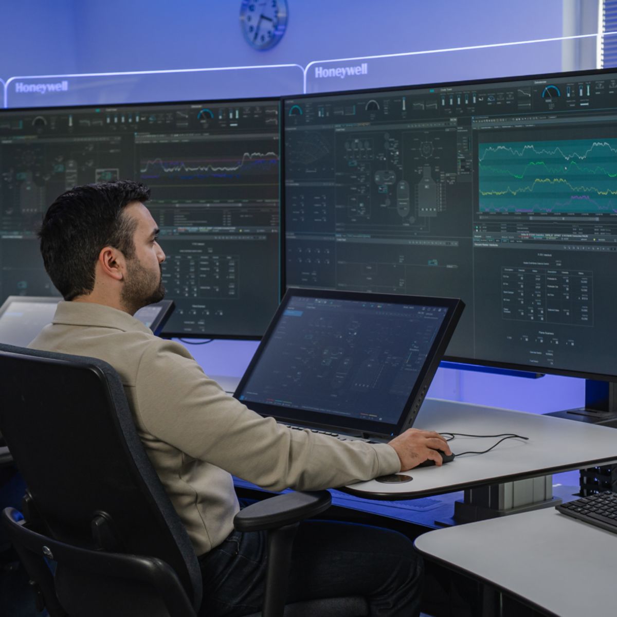 Professional working at a workstation in an operations center, interacting with screens and systems to manage complex data.
