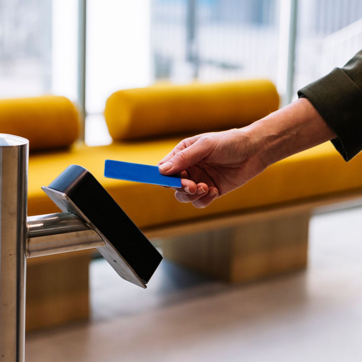 Hand holding security card over scanner on pole in lobby