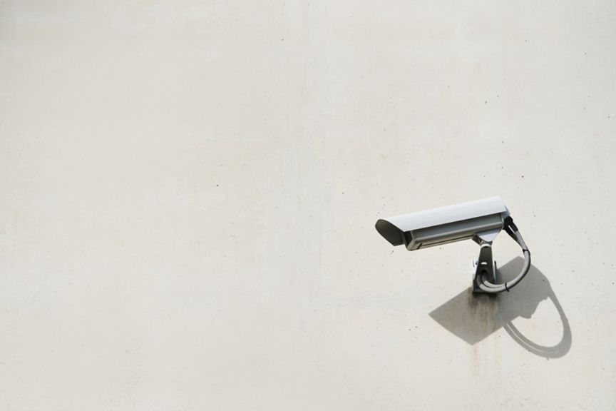 Close-up of a security camera hanging on the exterior wall of the building. Security concept.