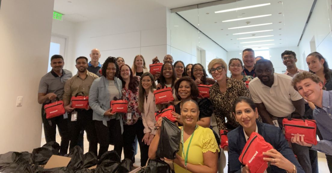 Group photo of employees holding Honeywell-branded kits, showcasing teamwork and engagement during an event.