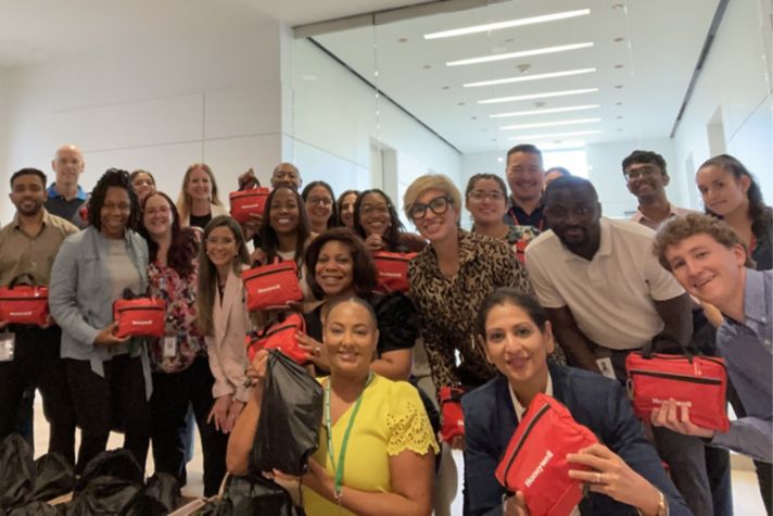 Group photo of employees holding Honeywell-branded kits, showcasing teamwork and engagement during an event.