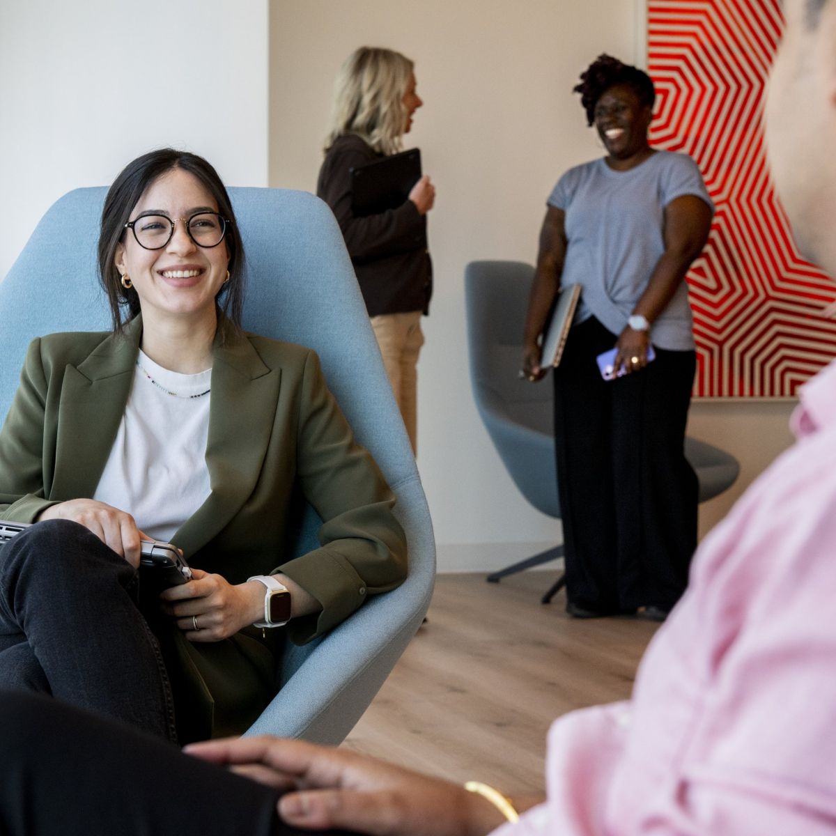 Diverse business team members engaging in a collaborative discussion within a modern office lounge setting.