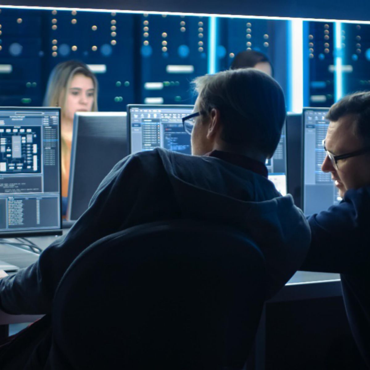 Professionals analyzing data in a cybersecurity operations center with multiple screens, representing threat monitoring and IT security systems.
