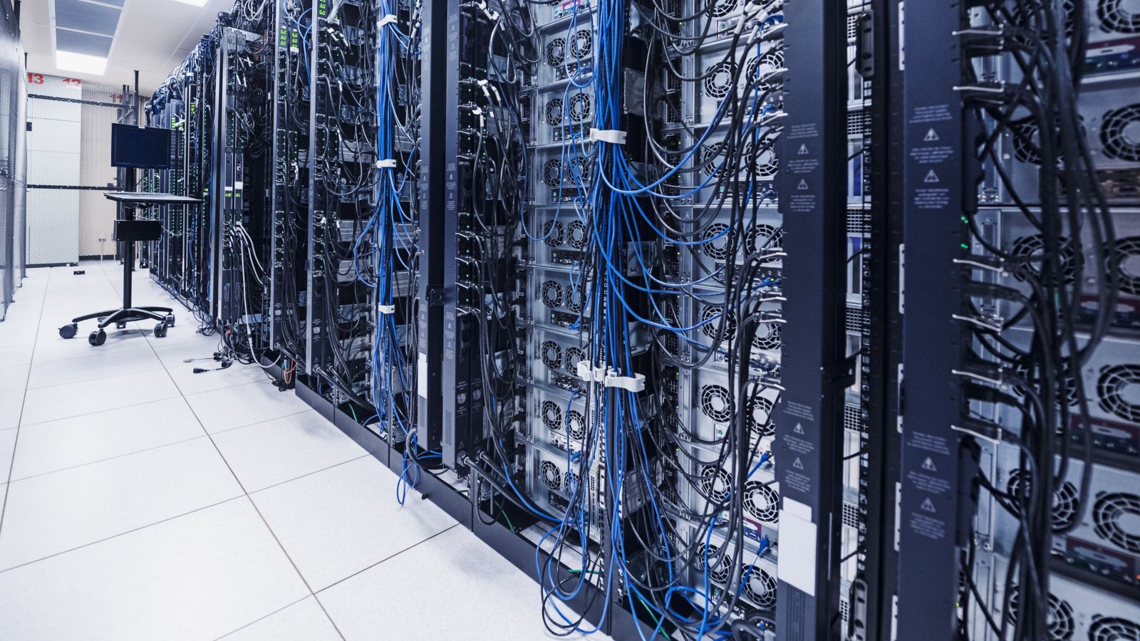 High-density server racks featuring intricate blue and black network cabling inside a modern industrial data center facility.