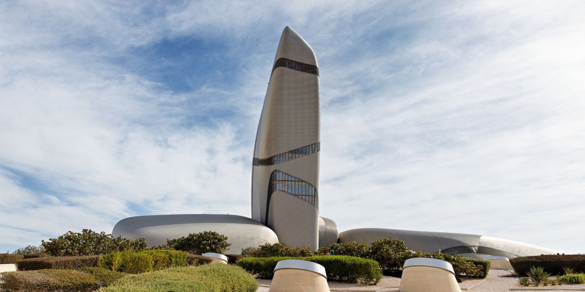 Futuristic cultural center tower in Dhahran with unique curved design under a bright sky.