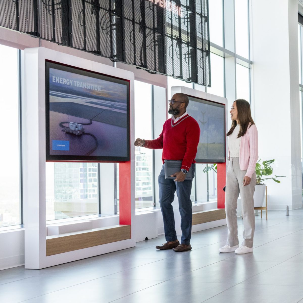 Employees interacting with digital screens in a modern workspace, highlighting collaboration, innovation, and technology‑driven communication.