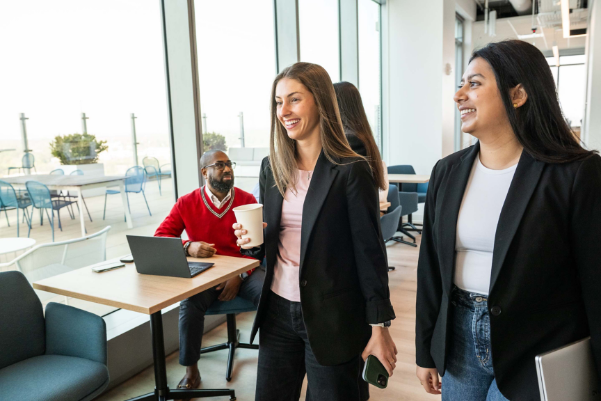 Professionals engaging and networking while walking through a contemporary office space, showcasing collaboration and dynamic work culture.