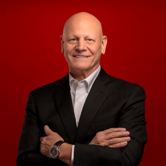 Professional portrait of Eric Seidel, captured against a bold red background.