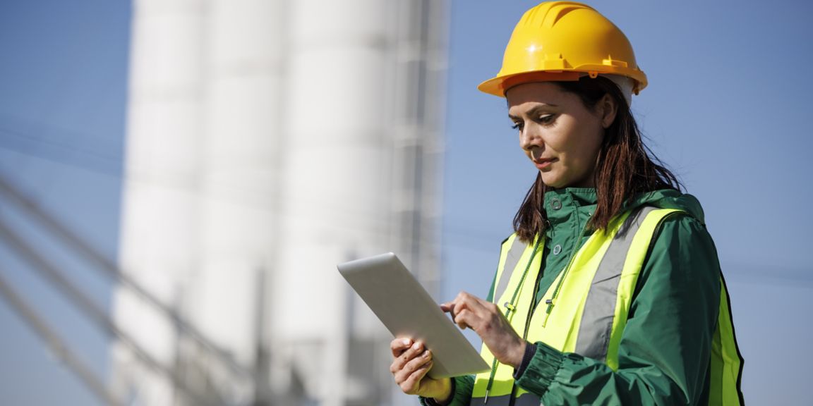 Portrait of female engineer with hardhat using digital tablet while working on her work site