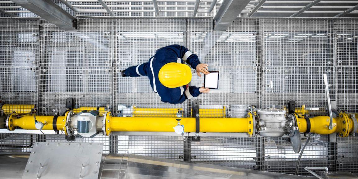 Top view of refinery worker walking by gas pipes, checking gasoline supply and installations in production plant.