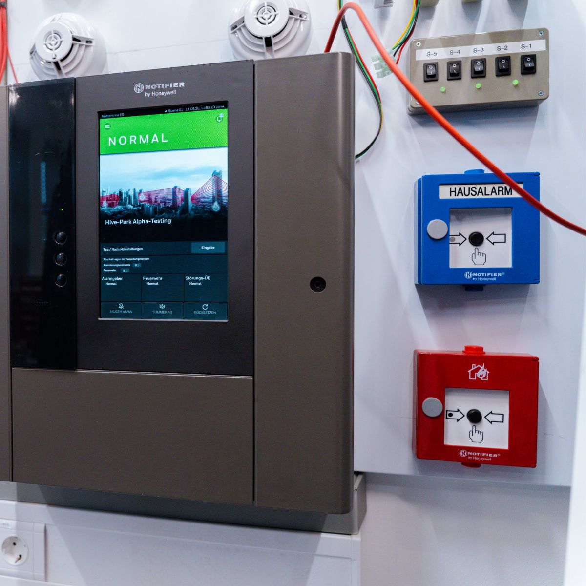A Notifier by Honeywell fire alarm control panel displaying a normal status on a white wall panel with various safety switches and indicators.