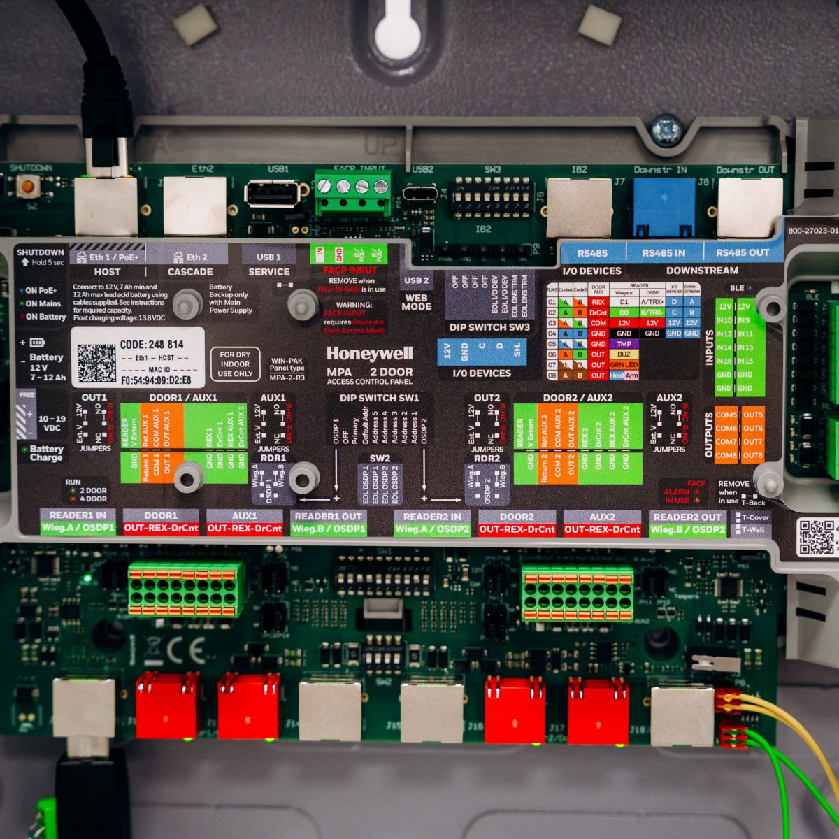 An overhead industrial view of a wired Honeywell MPA 2-door access control circuit board mounted inside a protective cabinet.
