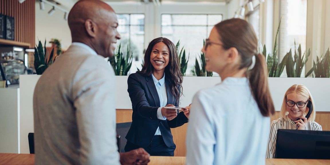 Guests interacting with staff in a contemporary hotel lobby, showcasing smooth check‑in service and a welcoming atmosphere.