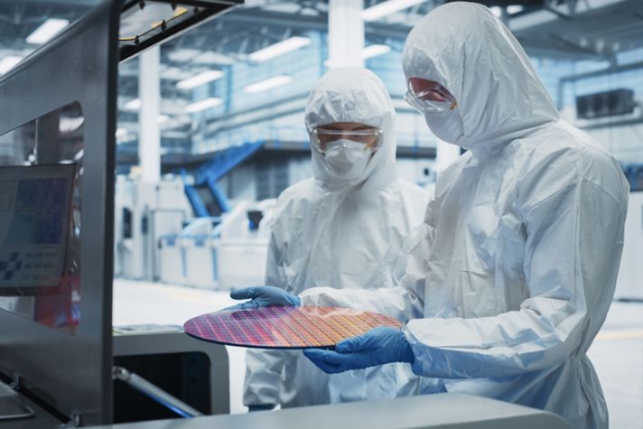 Semiconductor Production Process At Electronics Factory: Two Technicians In Sterile Suits Taking Out Silicon Wafer From Soldering Jet Printer And Inspecting It. Engineers Making Hardware For Computers