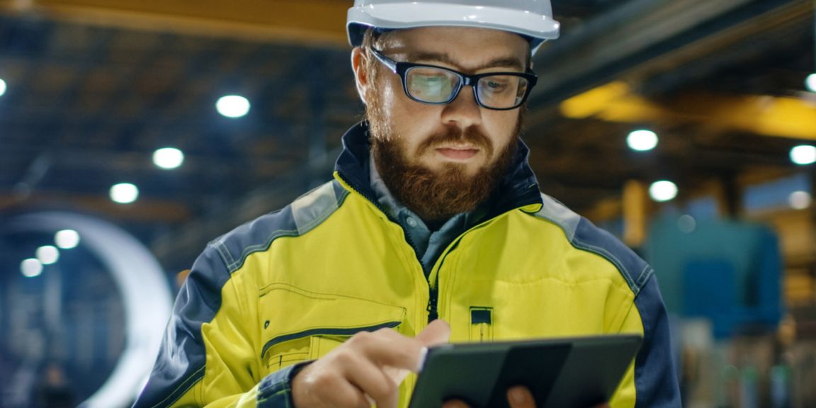 Operator using a digital device in an industrial environment to monitor combustion systems, supporting performance optimization, safety, and real-time operational control.