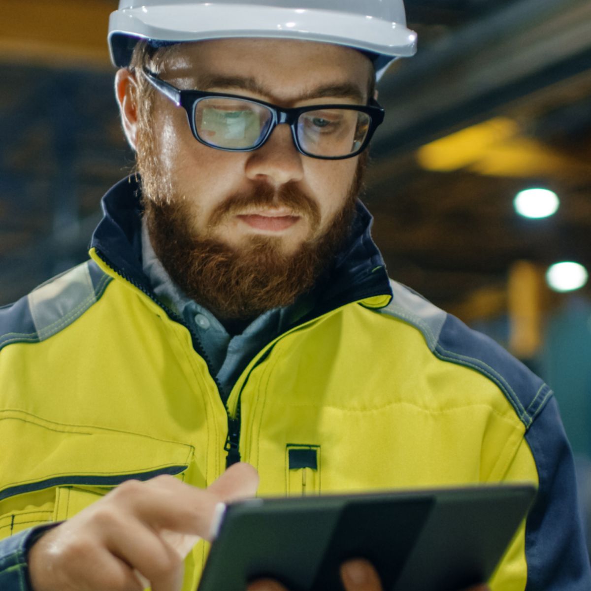 Operator using a digital device in an industrial environment to monitor combustion systems, supporting performance optimization, safety, and real-time operational control.
