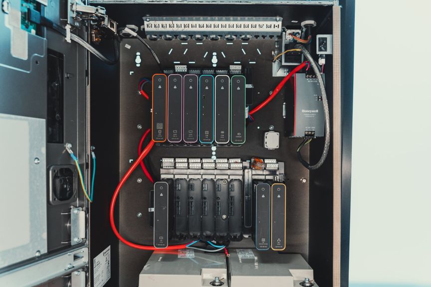 A view of an open industrial control cabinet featuring modular fire alarm system components and organized wiring.