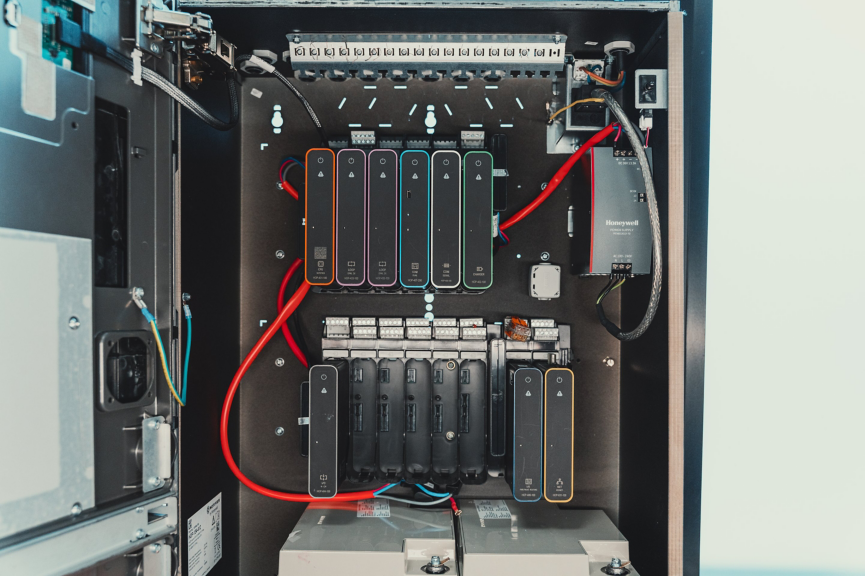A view of an open industrial control cabinet featuring modular fire alarm system components and organized wiring.