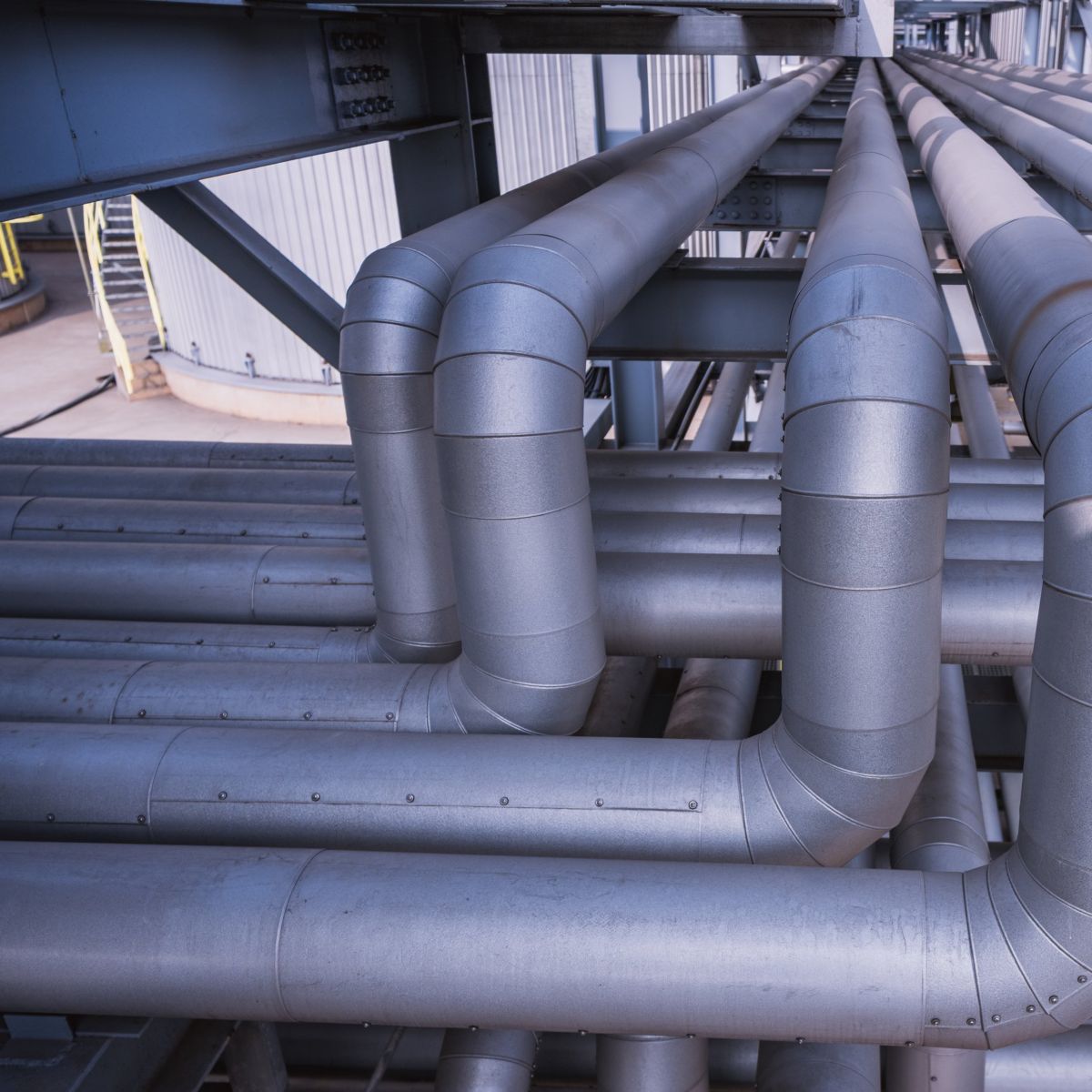 A complex network of insulated metal pipes and support structures at an industrial processing facility.