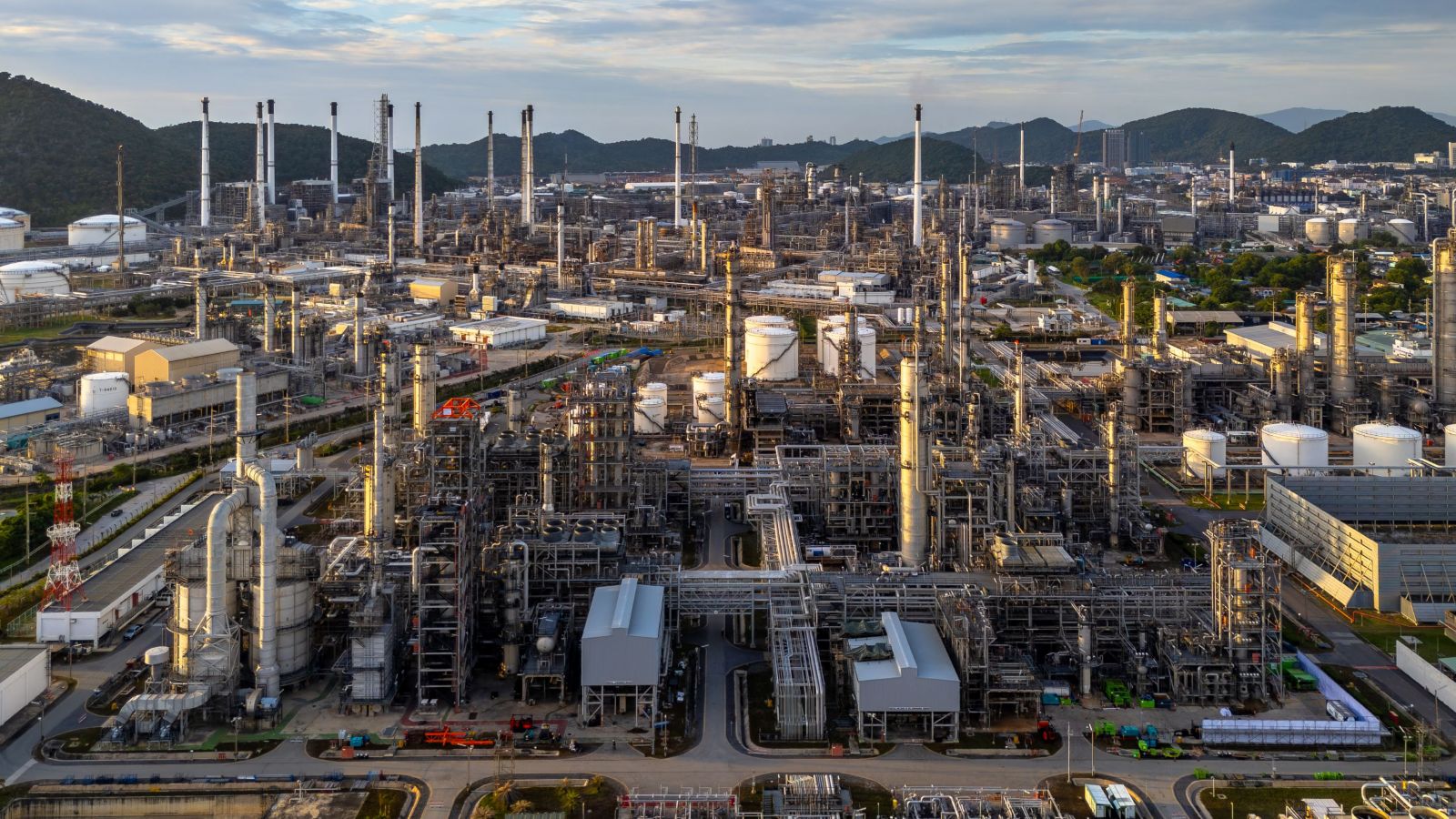 An overhead shot of a large industrial refinery complex, showcasing towers, pipes, and multiple storage units.
