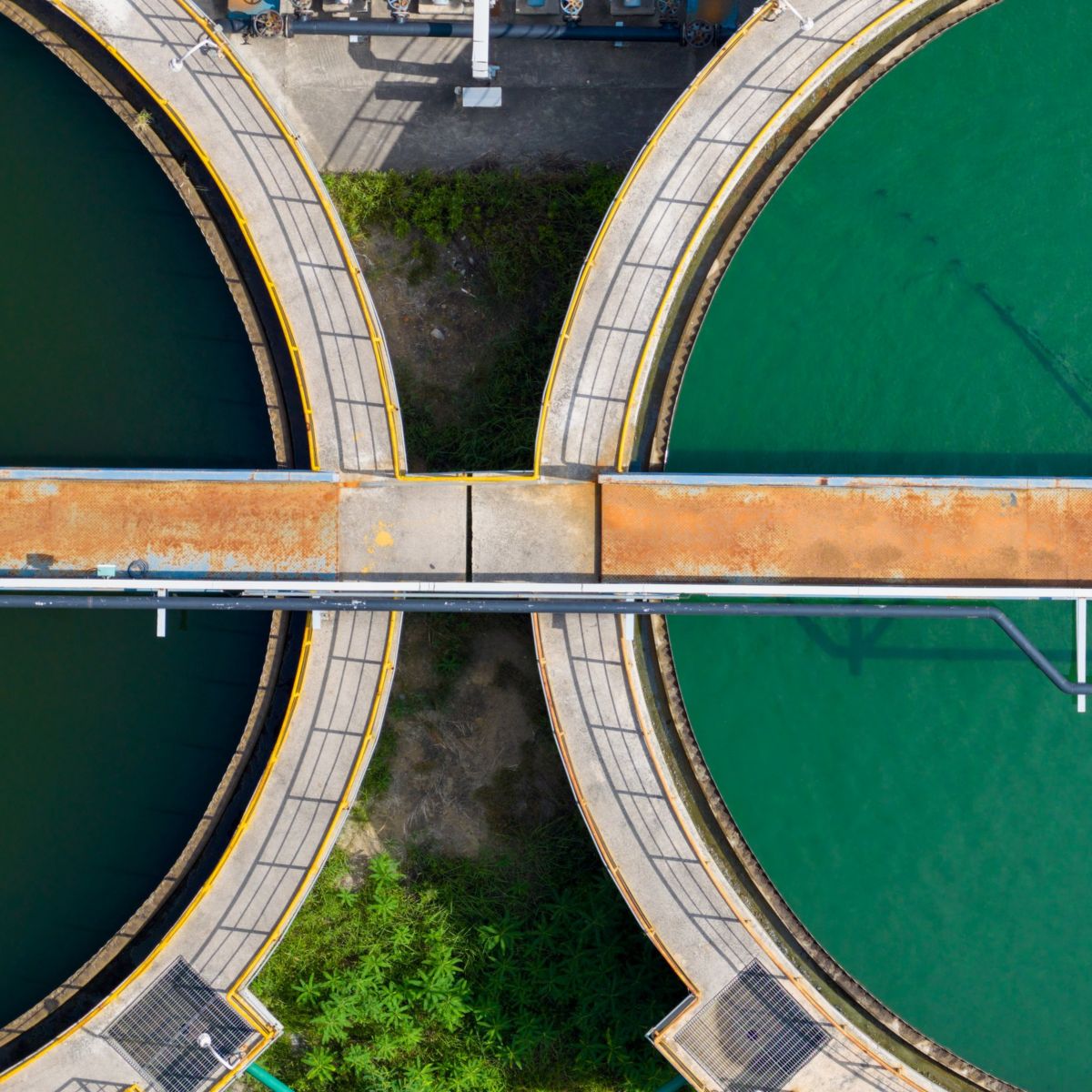 Aerial top-down view of industrial water treatment circular tanks and infrastructure.