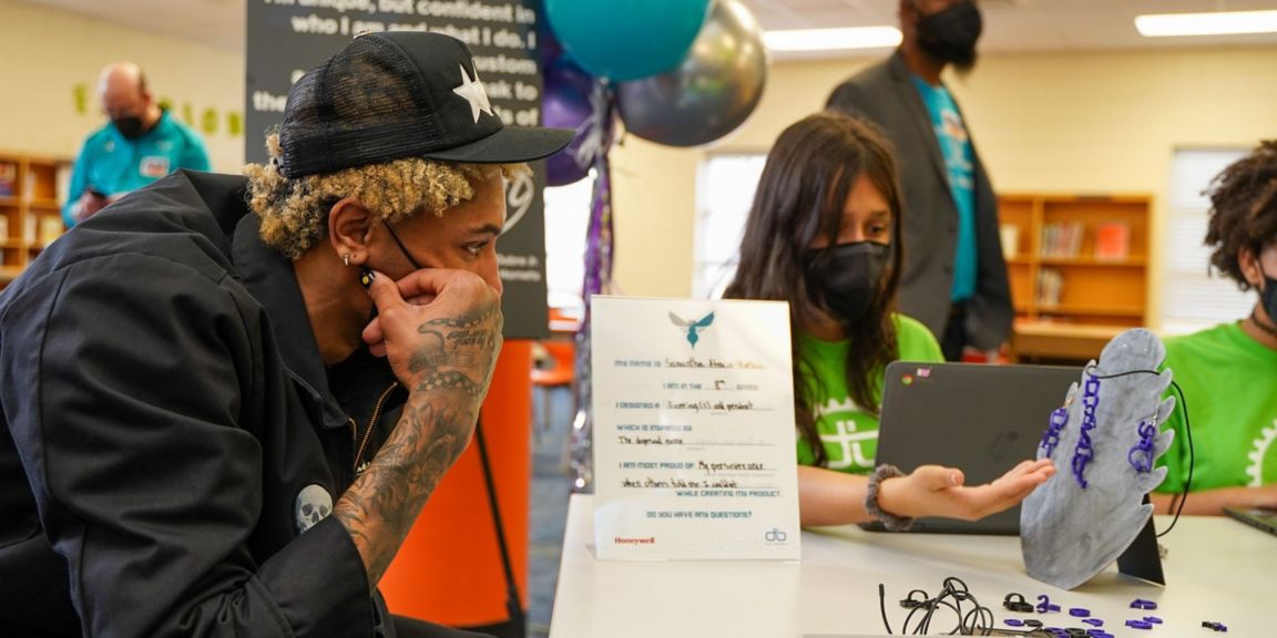 Kelly Oubre Jr. looks at a design made by Governors' Village STEM Academy eighth-grader Samantha Atencio-Hurtado.