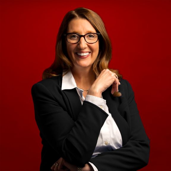 Professional portrait of Jennifer Reilly, captured against a bold red background.
