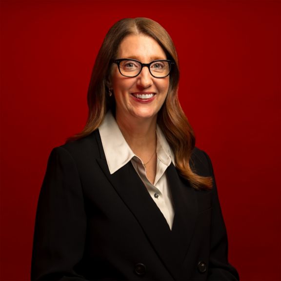 Professional portrait of Jennifer Reilly, captured against a bold red background.