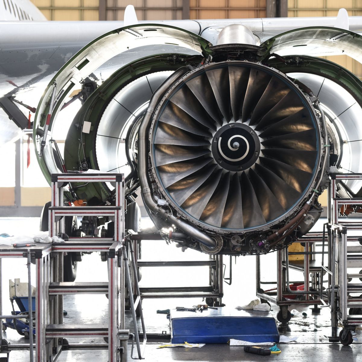 A turbofan engine of a commercial aircraft undergoes detailed technical inspection and maintenance within a professional aerospace hangar facility.