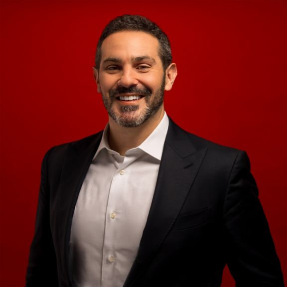 Professional portrait of Jimmy Steinberg, captured against a bold red background.