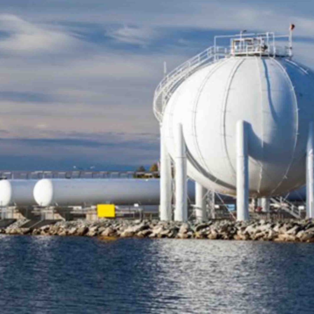 A gas storage facility featuring spherical tanks and cylindrical containers along a waterfront.