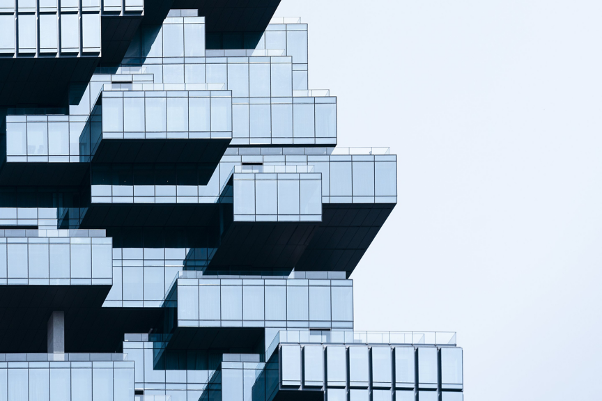 A minimalist architectural detail featuring modular glass building sections against a clean, bright sky.