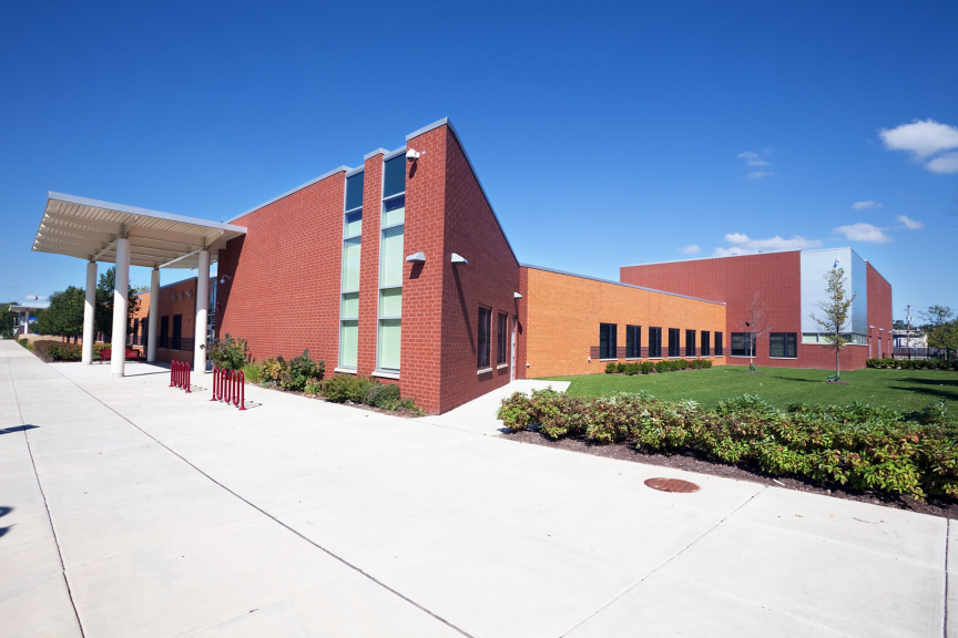 Exterior view of a contemporary brick educational facility featuring a covered walkway and clear blue sky.