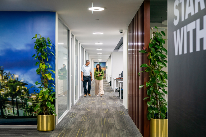 Contemporary office hallway with plants, glass walls, and clean design promoting a healthy and productive workplace.