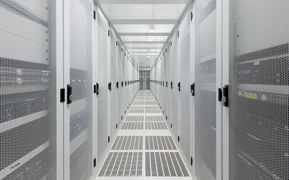 A symmetrical view down a bright, white data center aisle featuring rows of high-security perforated metal server cabinets.