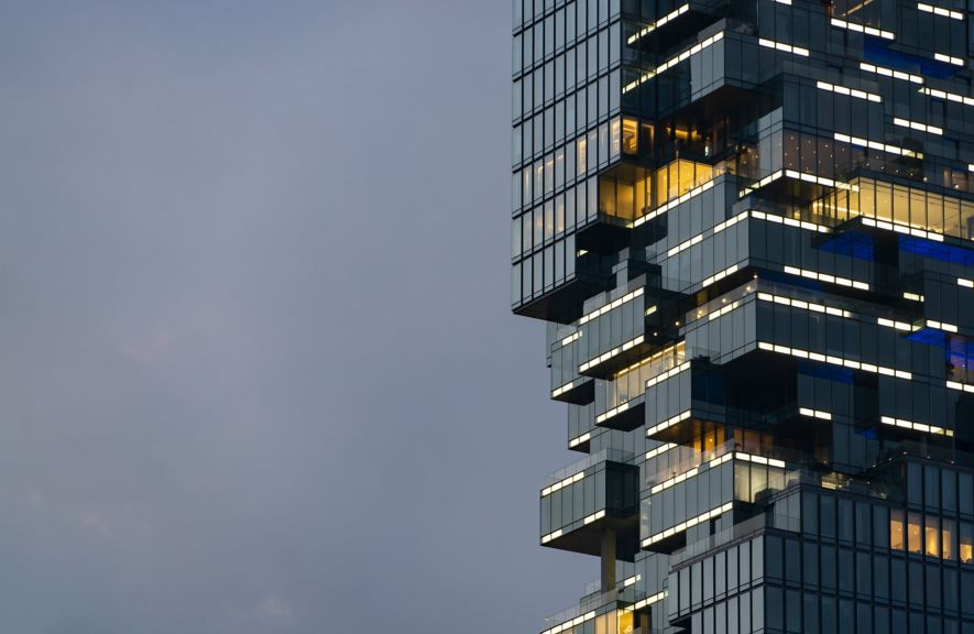 A sharp, architectural shot highlighting the pixelated, cantilevered glass facade of a modern skyscraper at dusk with glowing interior lights.