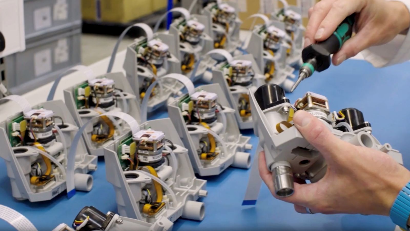 A technician assembles electronic components, showcasing precision in a manufacturing environment filled with parts.