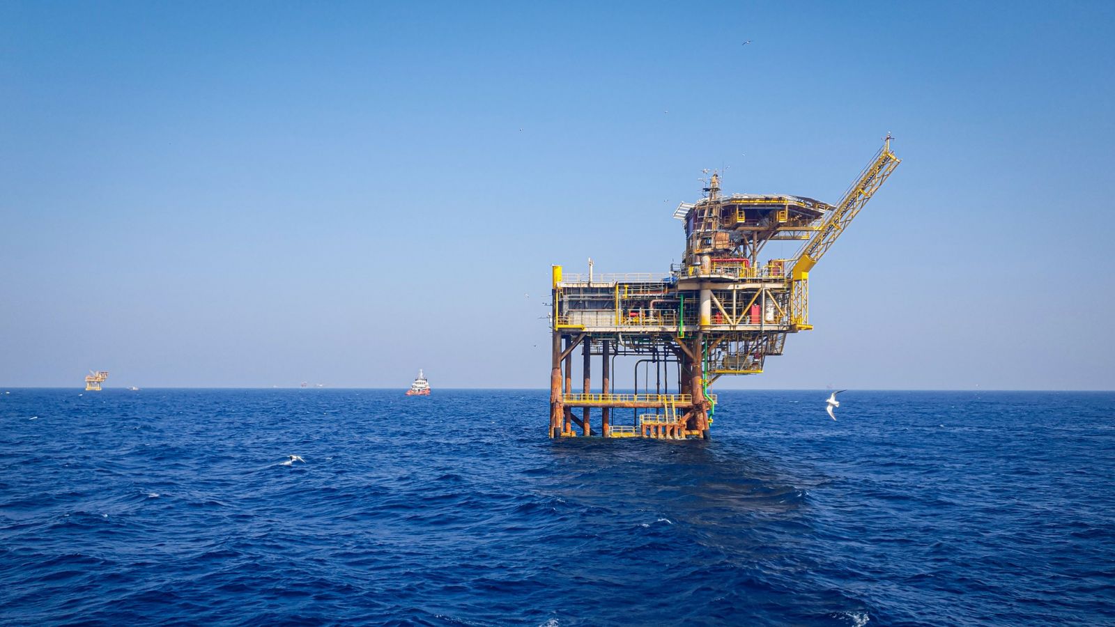 A modern offshore oil rig stands tall in the deep blue sea, showcasing the vastness of marine energy extraction.