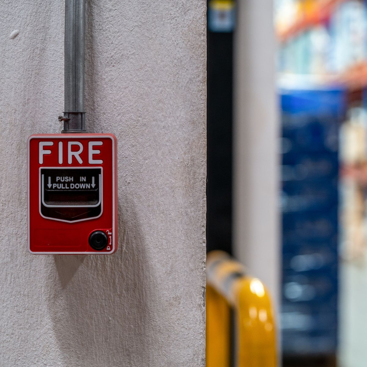 Red fire alarm switch on the concrete wall in the office building. Industrial fire warning system equipment for emergency.