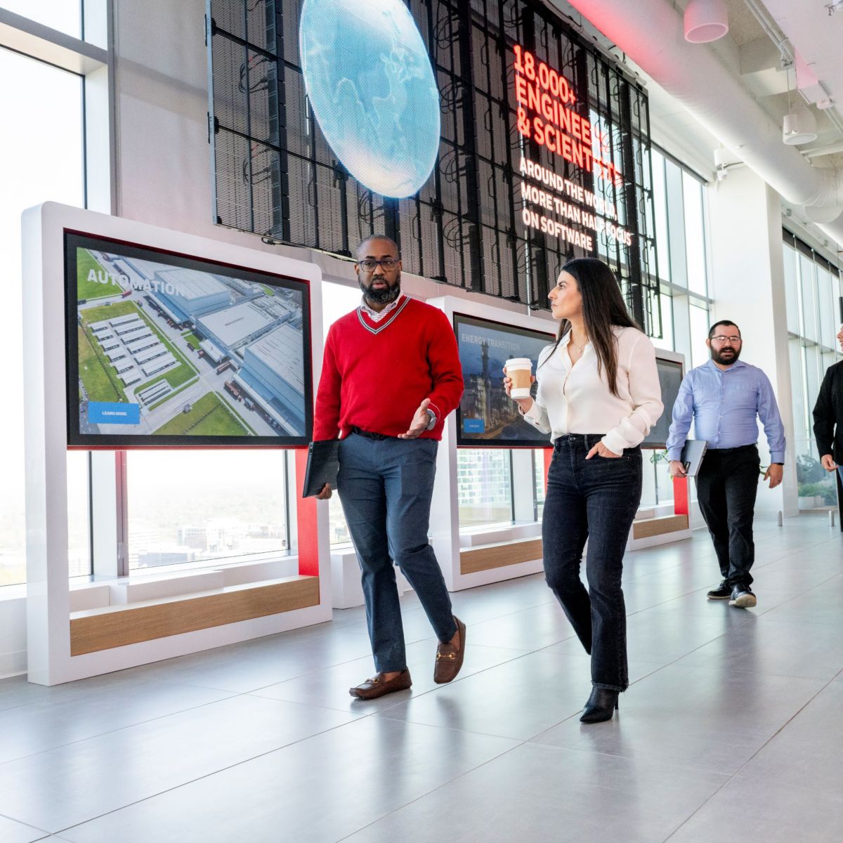 A business meeting at Honeywell with a speaker presenting to a group of professionals, showcasing teamwork and innovation in a modern office space.