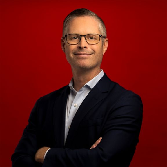 Corporate portrait of Pete Lau, captured against a bold red backdrop.