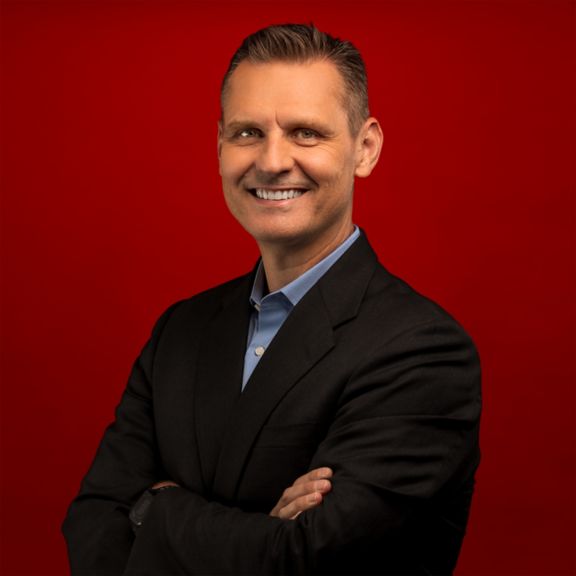 Professional portrait of Peter Kropik, captured against a bold red background.