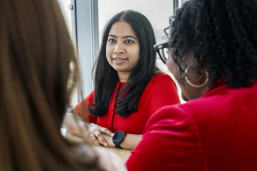 Colleagues engaged in a focused discussion in a corporate office, showcasing collaboration, communication, and teamwork.