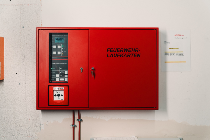 A wall-mounted red fire alarm control panel with instructional navigation cards for emergency responders in a corporate facility.