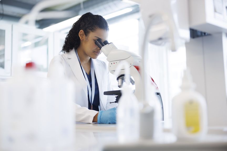 A focused scientist in a lab coat performs microscopic research in a modern laboratory setting.