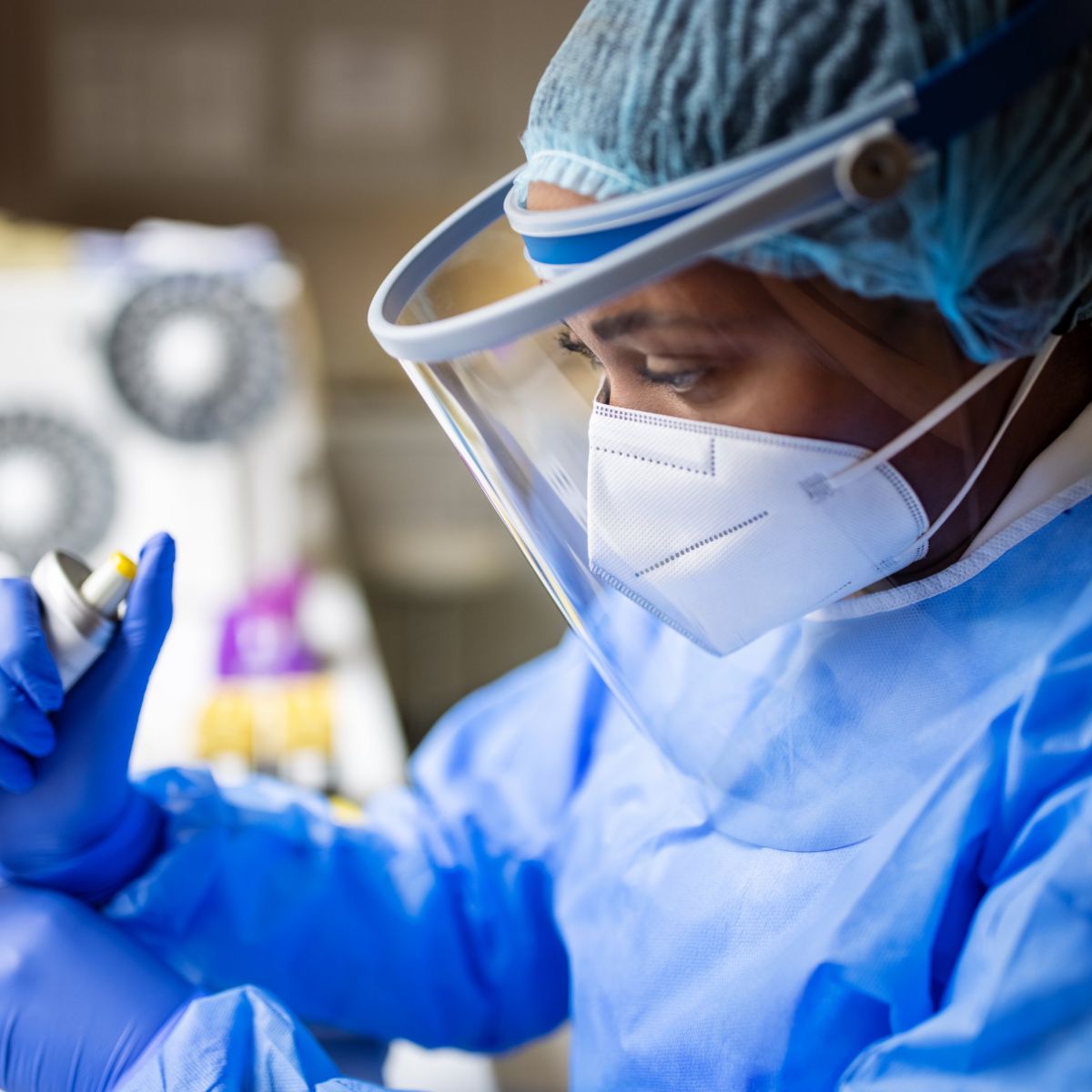 A laboratory scientist in full protective gear performs precise medical research using a micropipette.