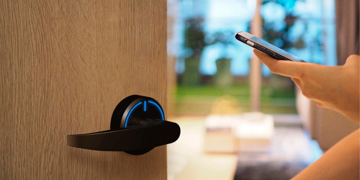 Close-up of a smartphone being used to unlock a door with a smart electronic lock featuring illuminated access indicators, demonstrating mobile credential-based entry.