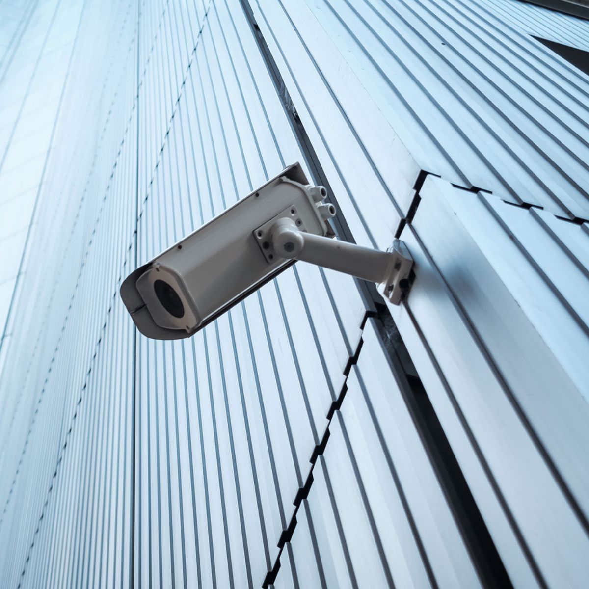 Security camera mounted on exterior of a modern glass building