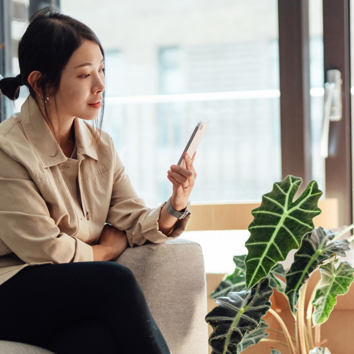Person sitting near stacked boxes using a smartphone in a bright living 